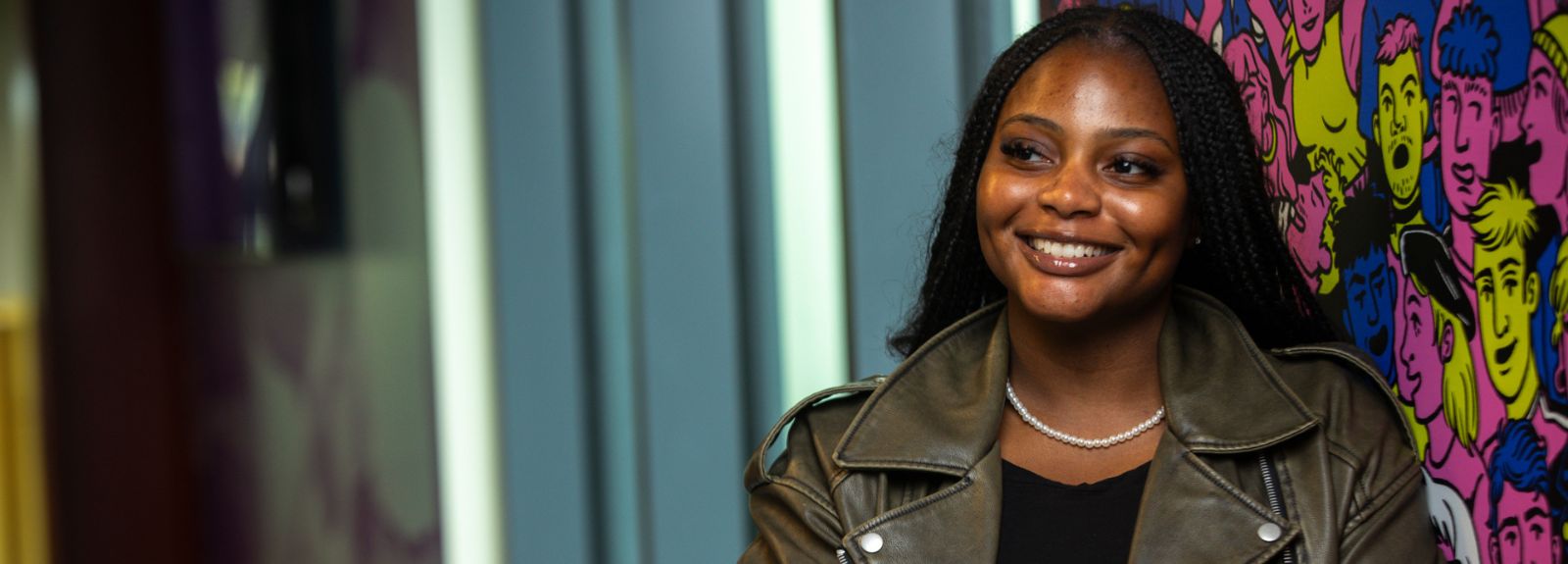 female student standing smiling to camera with arms folded